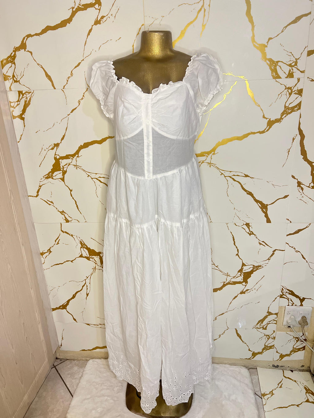A white tiered dress with a sheer mesh corset-style bodice and ruffled cap sleeves 