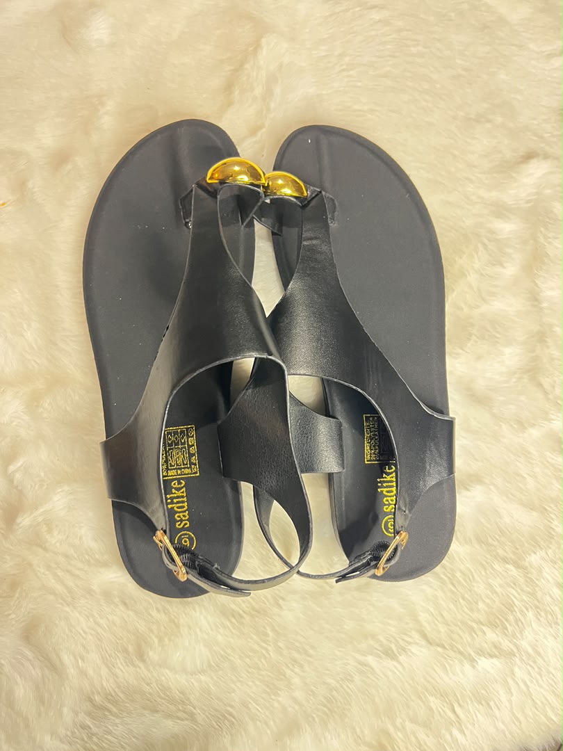 Black flat T-strap sandals with gold-tone decorative accents