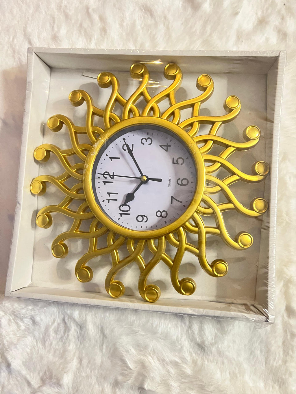 A decorative wall clock with a gold sunburst frame