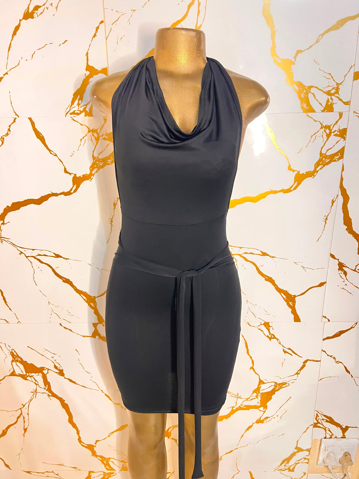 A sleeveless black cowl-neck mini dress with a tie waist