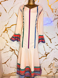 A long cream-colored dress features colorful striped details  