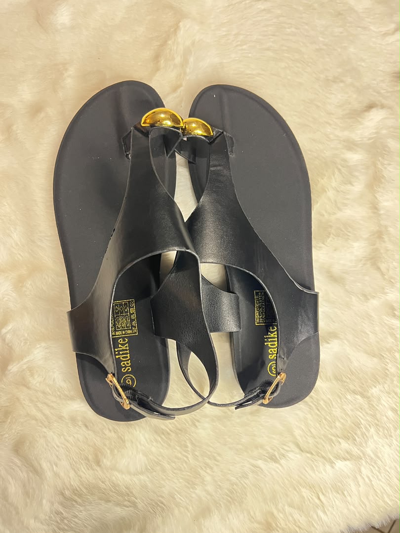 Black flat T-strap sandals with gold-tone decorative accents
