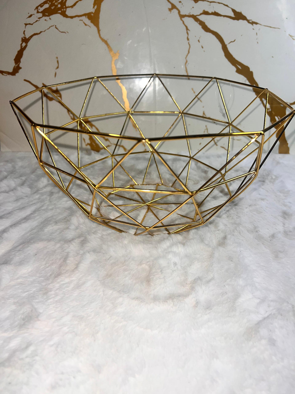 A gold geometric fruit bowl with a faceted triangular pattern.
