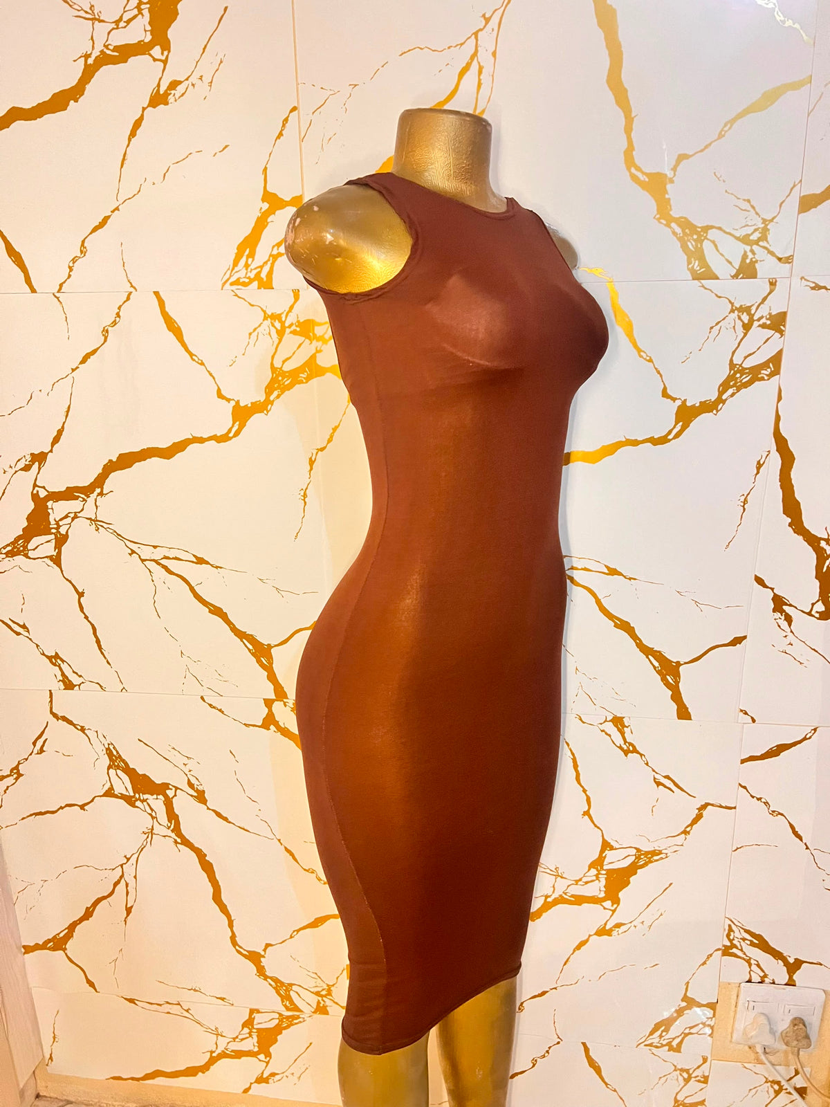 A sleeveless, bodycon midi dress in a warm rust brown color