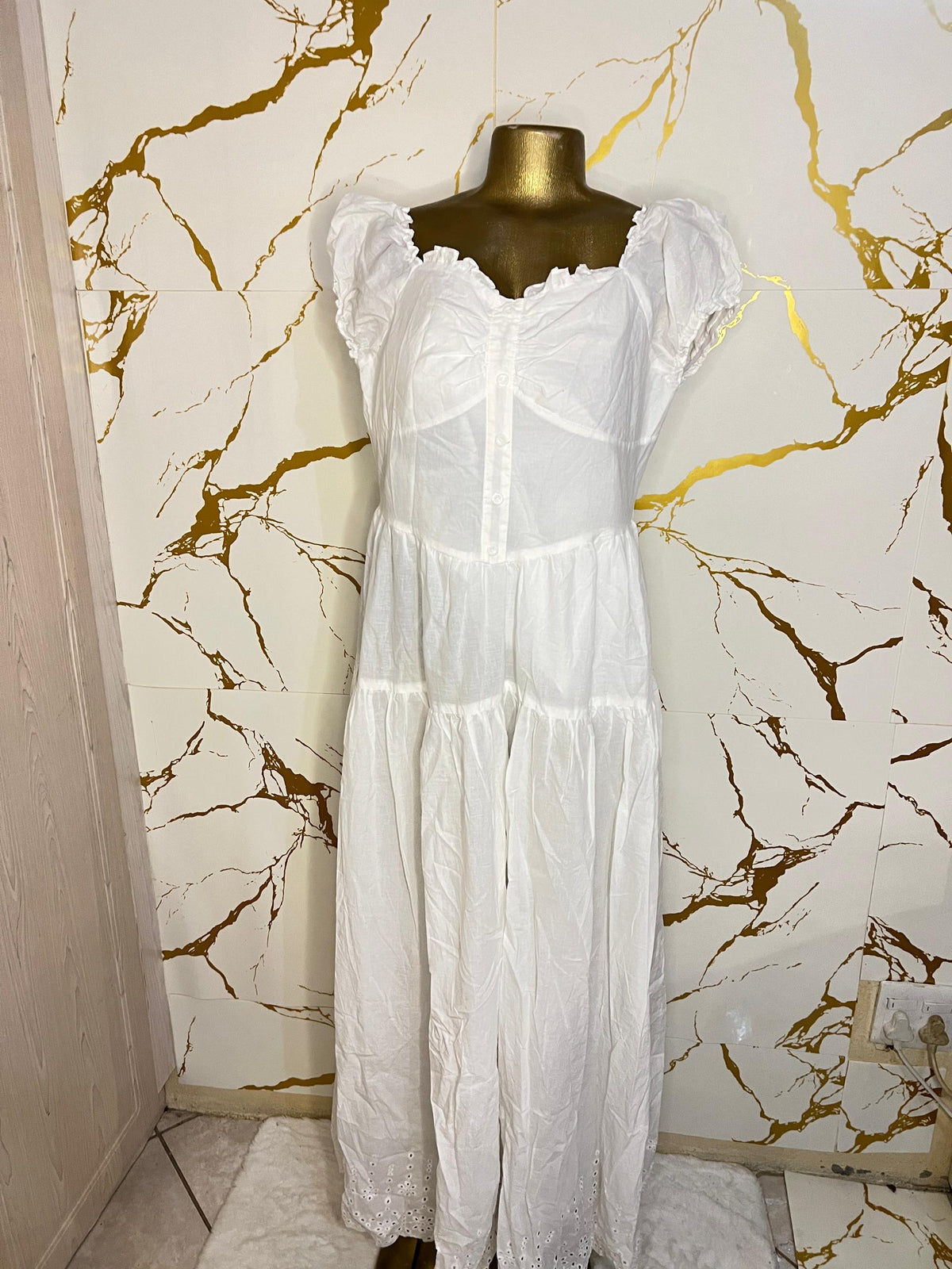 A white tiered dress with a sheer mesh corset-style bodice and ruffled cap sleeves