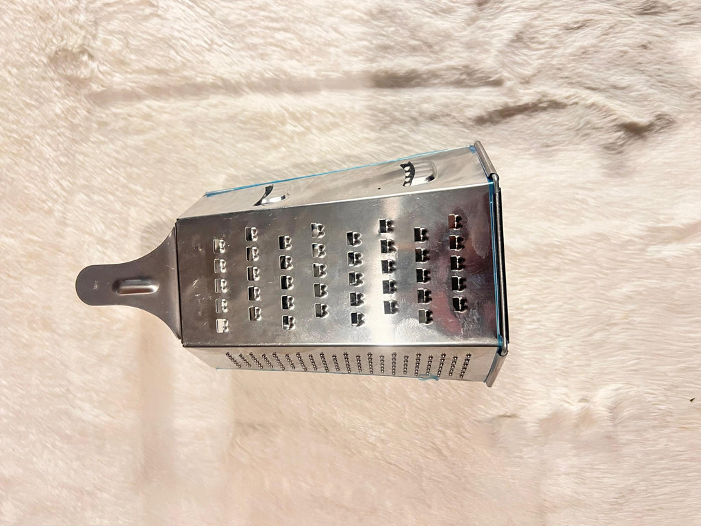 A stainless steel box grater with a dark gray handle