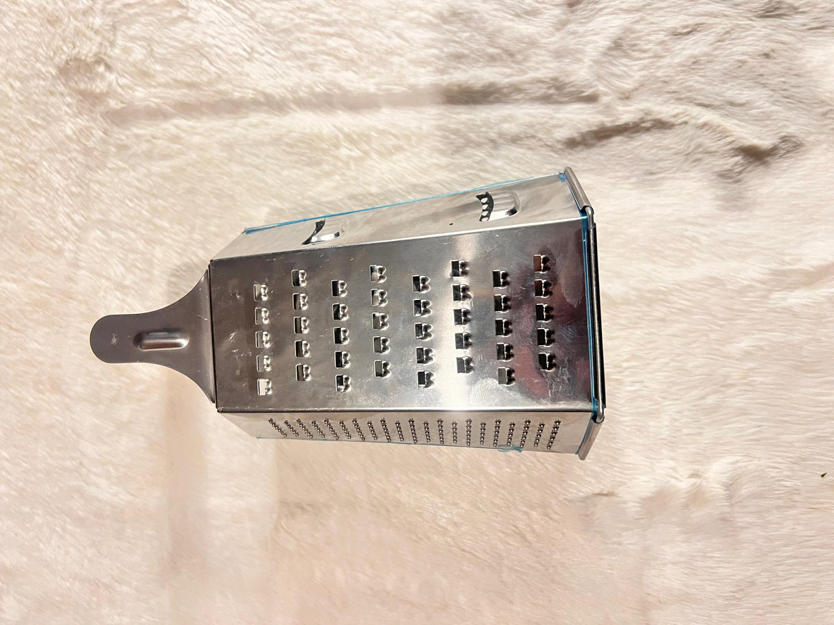 A stainless steel box grater with a dark gray handle