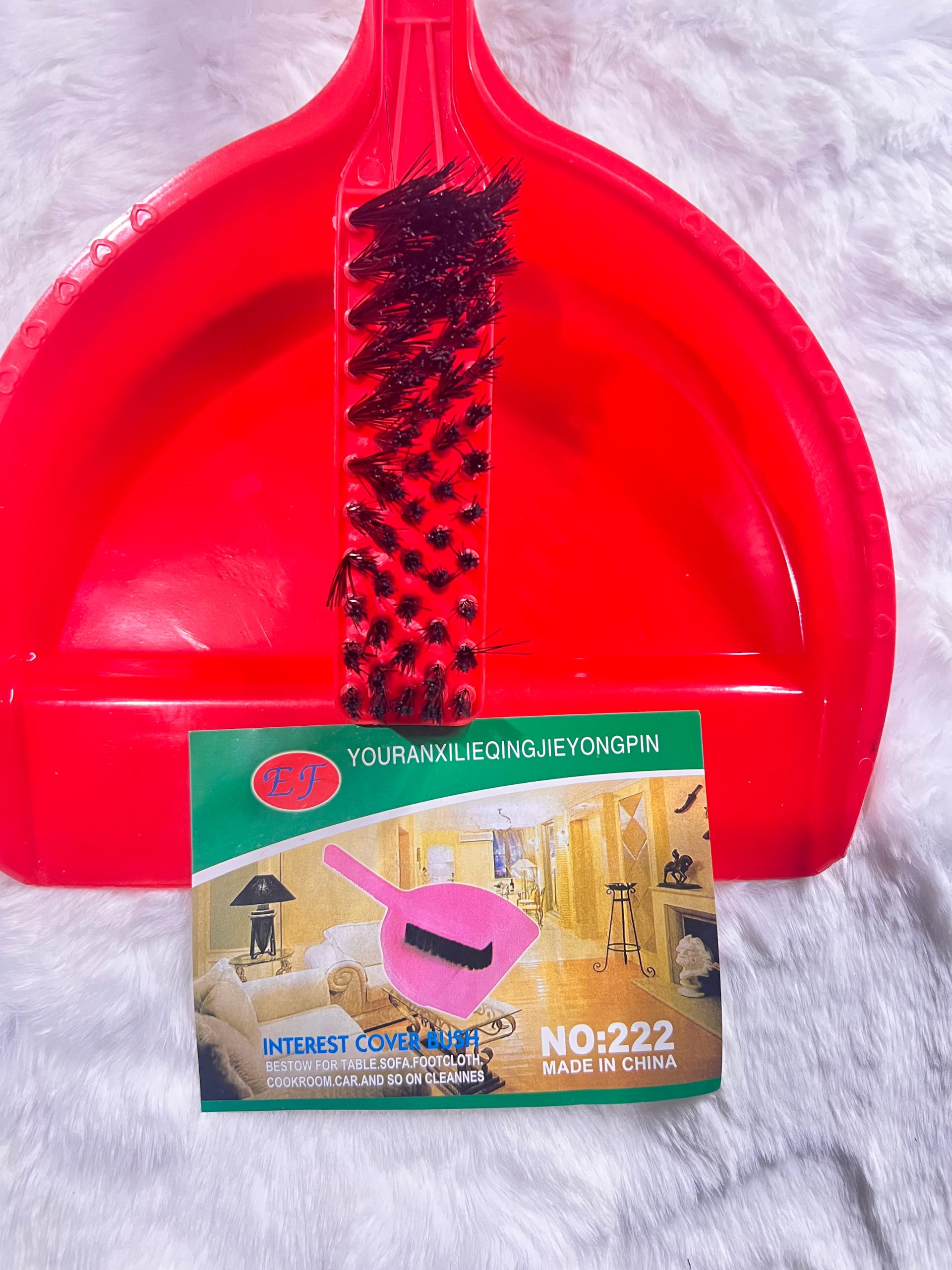 A red plastic dustpan with a wire brush