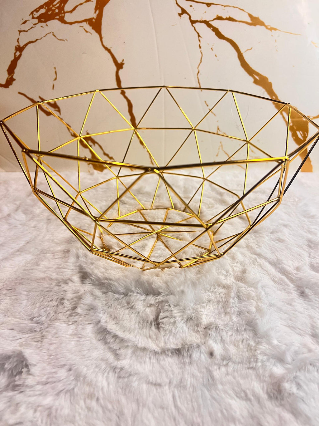 A gold geometric fruit bowl with a faceted triangular pattern.