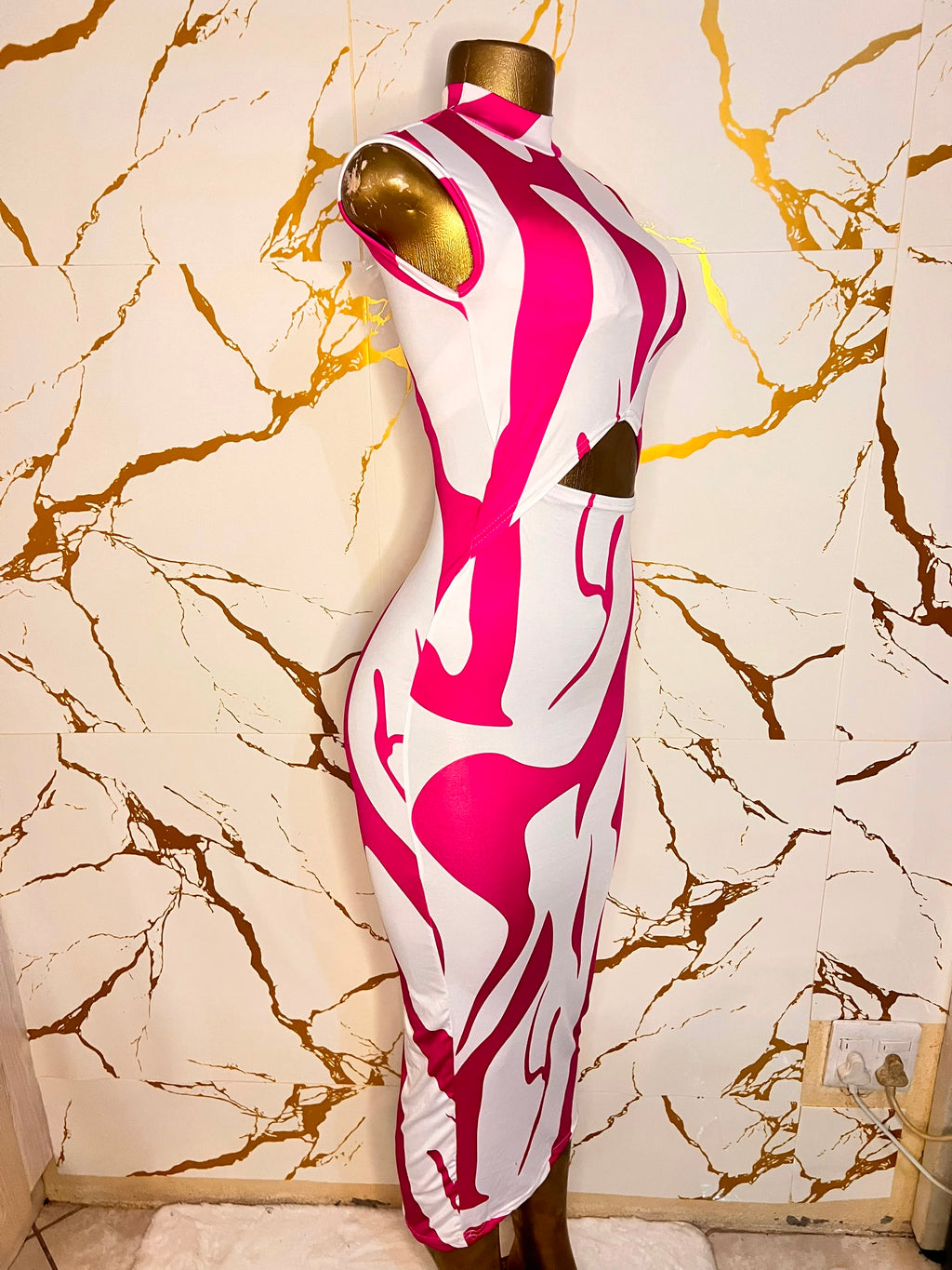Sleeveless bodycon dress displayed on a mannequin, featuring a bold abstract pattern in hot pink