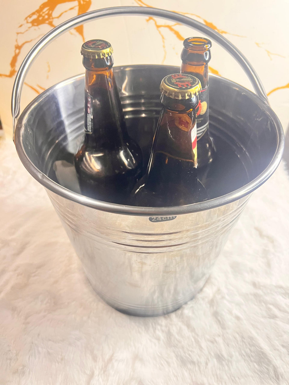A shiny silver ice metal bucket with a curved handle