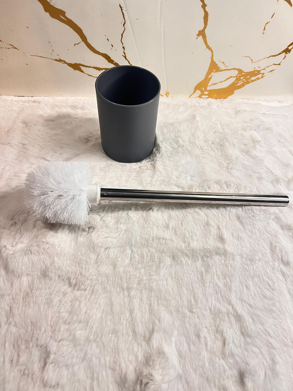 A toilet brush with white bristles and a silver metal handle 