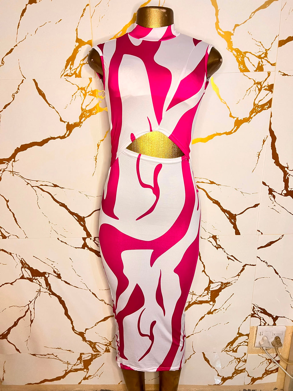 A sleeveless bodycon dress displayed on a mannequin, featuring a bold abstract pattern in hot pink