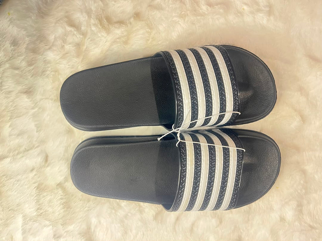 Adidas slide sandals with black footbeds and white stripes on the straps