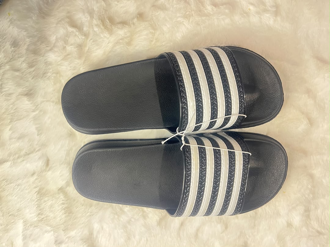 Adidas slide sandals with black footbeds and white stripes on the straps