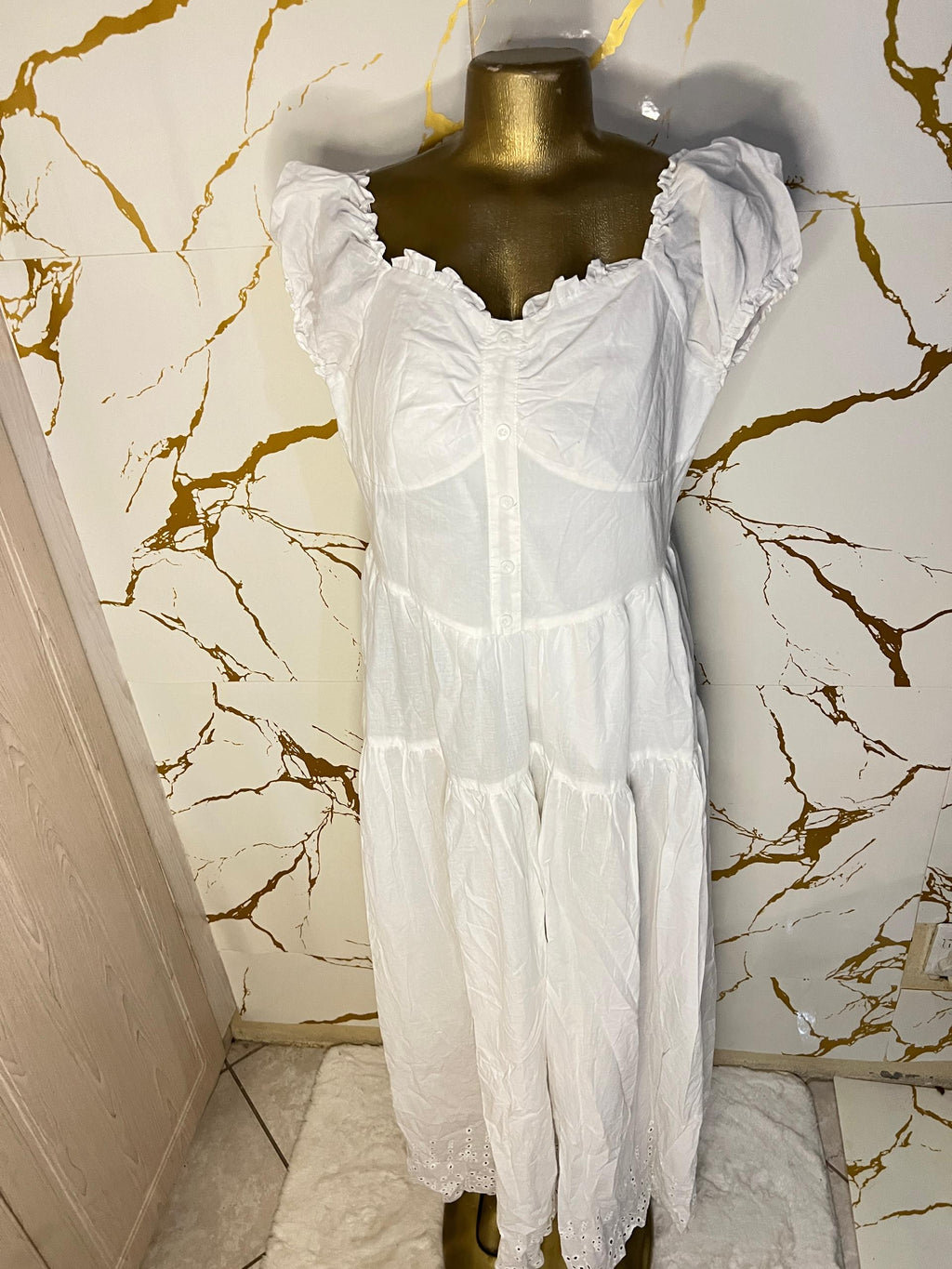 A white tiered dress with a sheer mesh corset-style bodice and ruffled cap sleeves