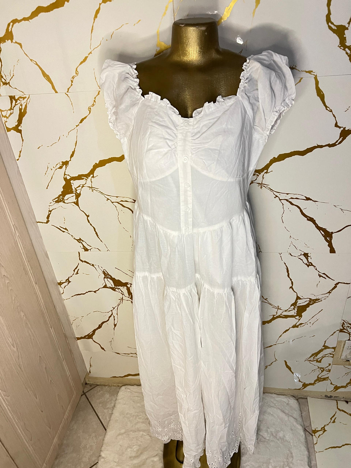 A white tiered dress with a sheer mesh corset-style bodice and ruffled cap sleeves