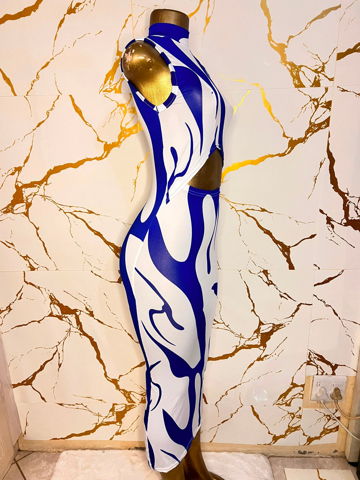 A sleeveless bodycon dress with a bold blue and white abstract wavy pattern