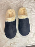 A pair of dark navy blue slip-on slippers with cream faux-fur trim, displayed on a white faux-fur surface.