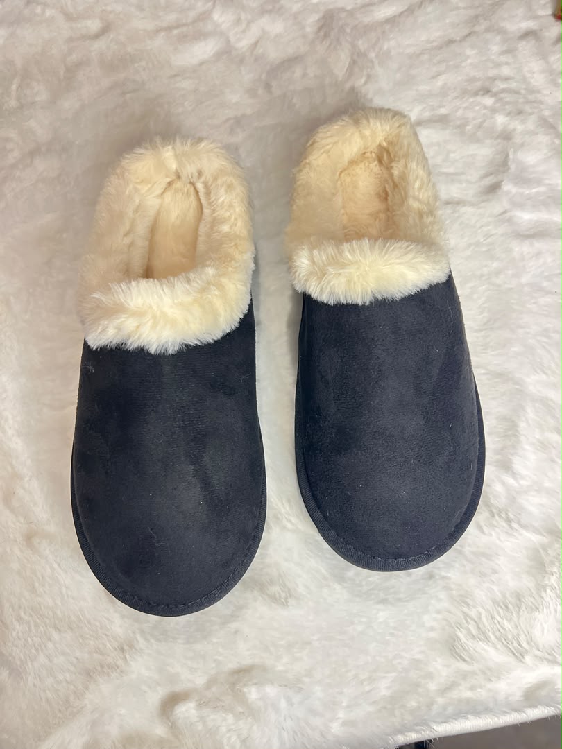 A pair of dark navy blue slip-on slippers with cream faux-fur trim, displayed on a white faux-fur surface.