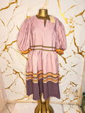 A pink dress has puff sleeves, a split neckline with decorative trim, a patterned waistband