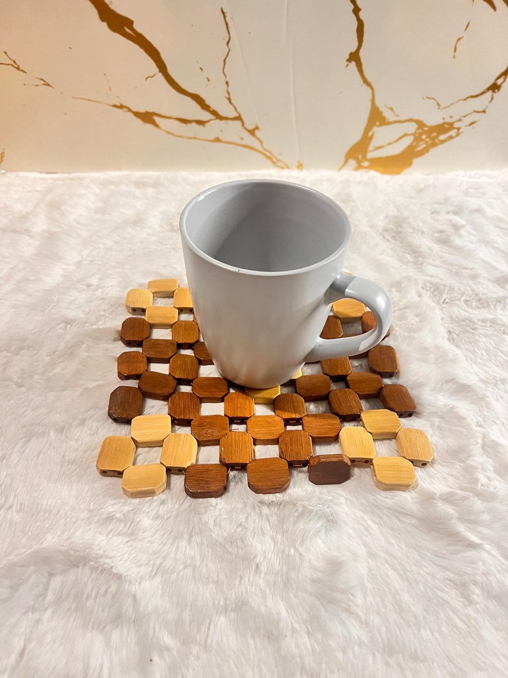 Coaster mat made of small octagonal wooden beads in various natural wood tones.