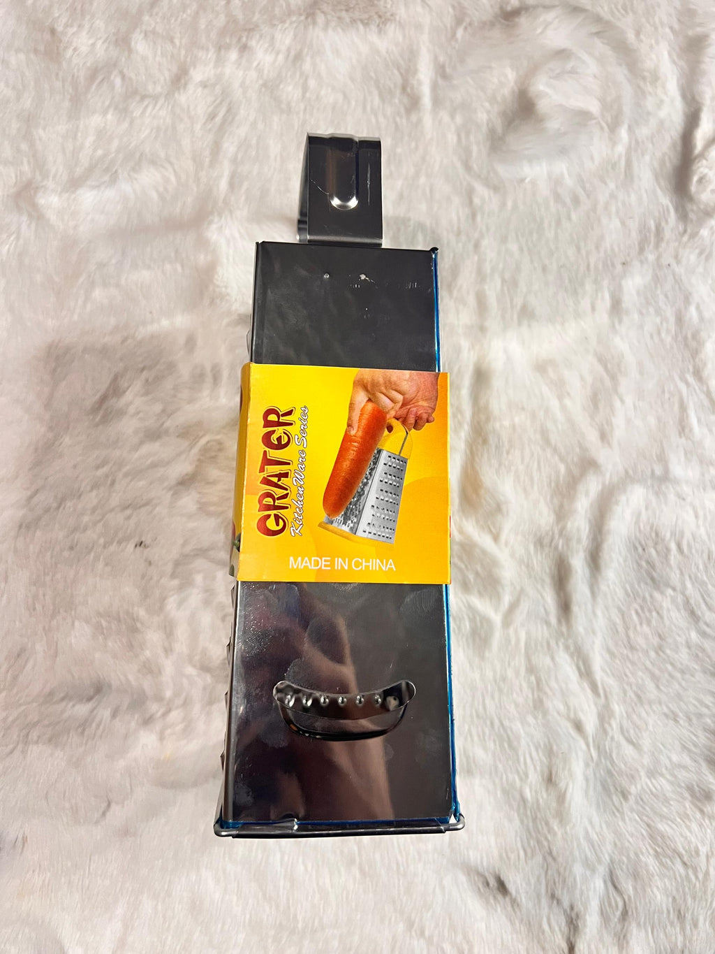 A stainless steel box grater with a black handle