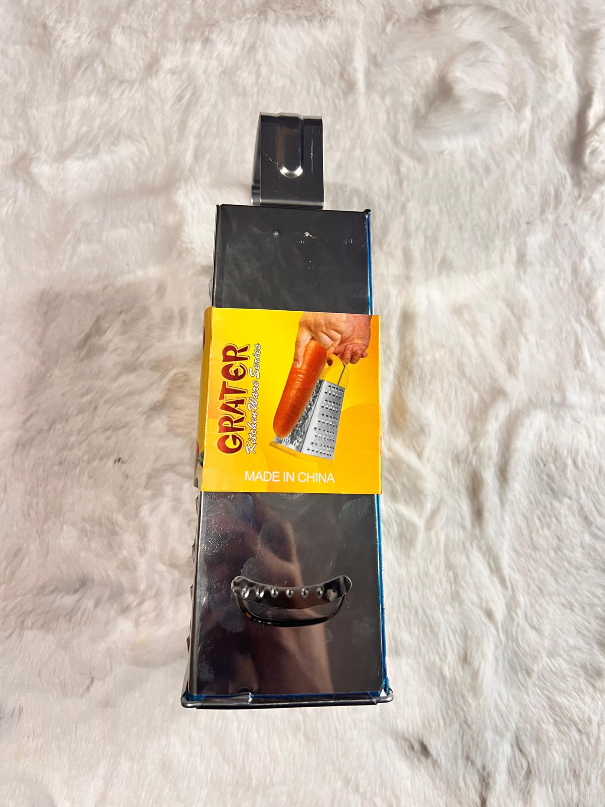 A stainless steel box grater with a black handle