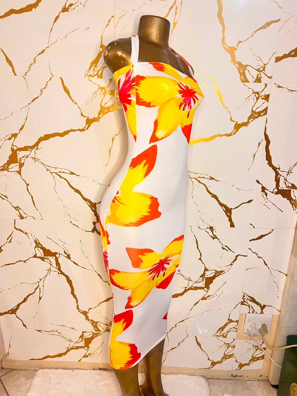 white halter-neck bodycon dress with a bold yellow and orange flower print