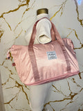 A shiny light pink zippered duffel bag with dual shoulder straps