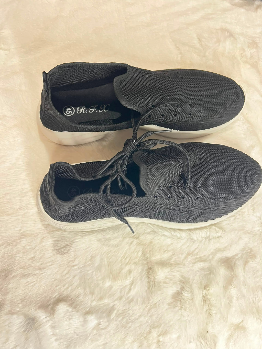 A pair of dark gray knit slip-on sneakers with white soles, displayed on a white faux fur surface. The brand name '奥天儿' is visible on the inner sole of the top shoe.