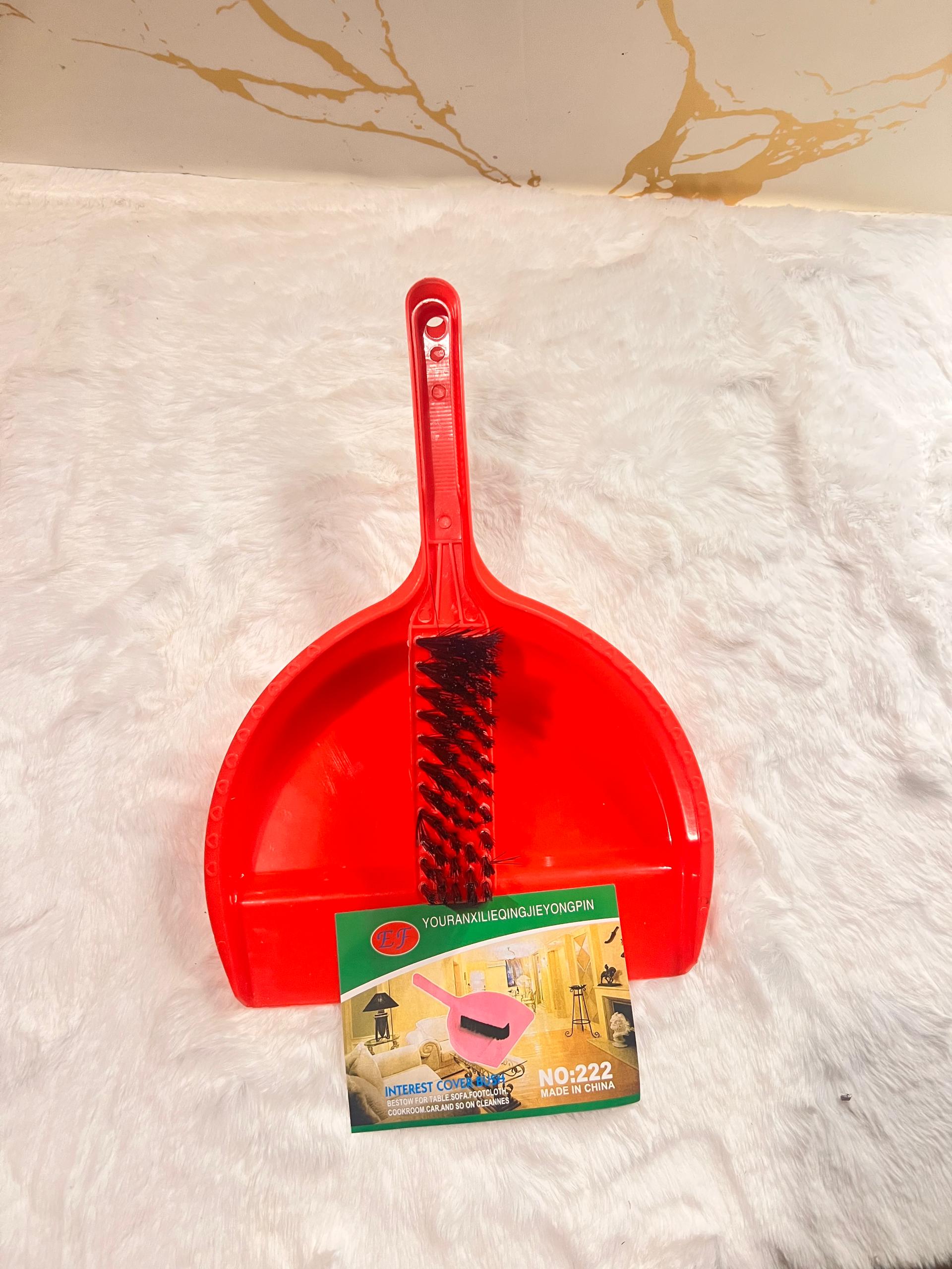 A red plastic dustpan with an integrated black wire brush on the front