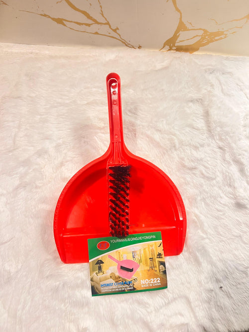 A red plastic dustpan with an integrated black wire brush on the front
