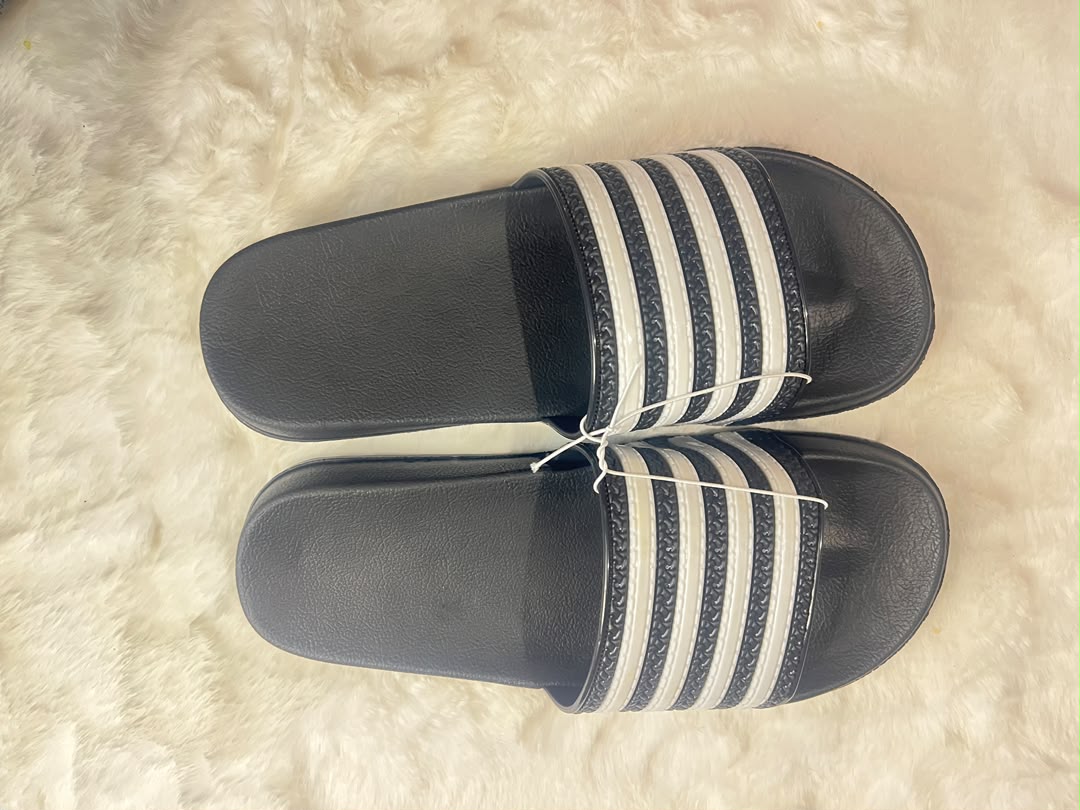 Adidas slide sandals with black footbeds and white stripes on the straps