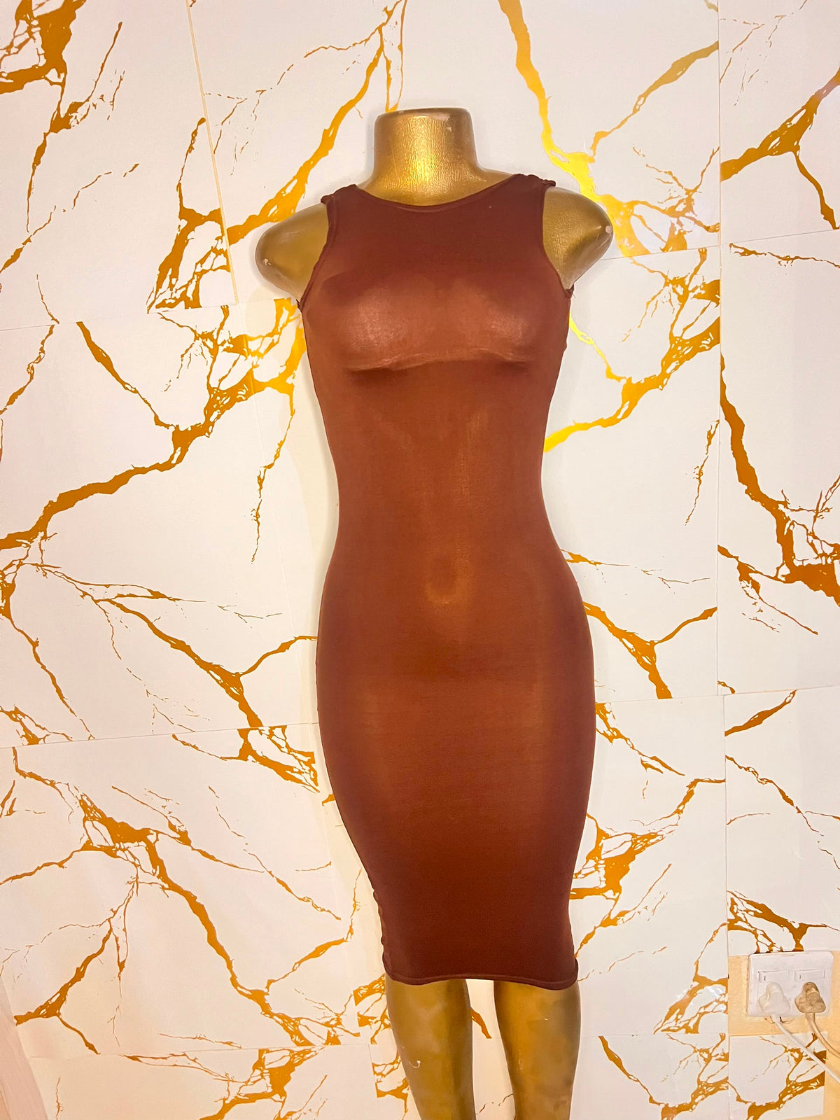 A sleeveless, bodycon midi dress in a warm rust brown color