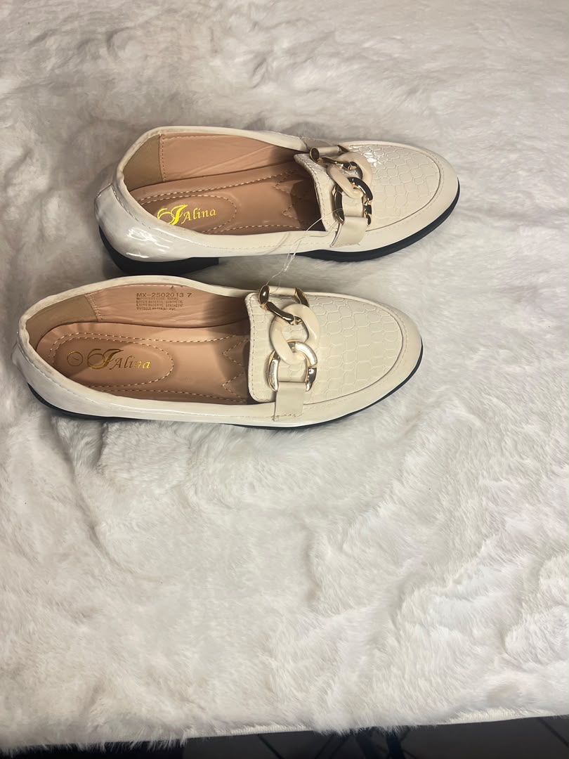 cream-colored loafers with a textured toe cap and a chunky gold-tone chain