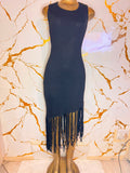 A sleeveless ribbed knit bodycon dress in black with a fringe hem,