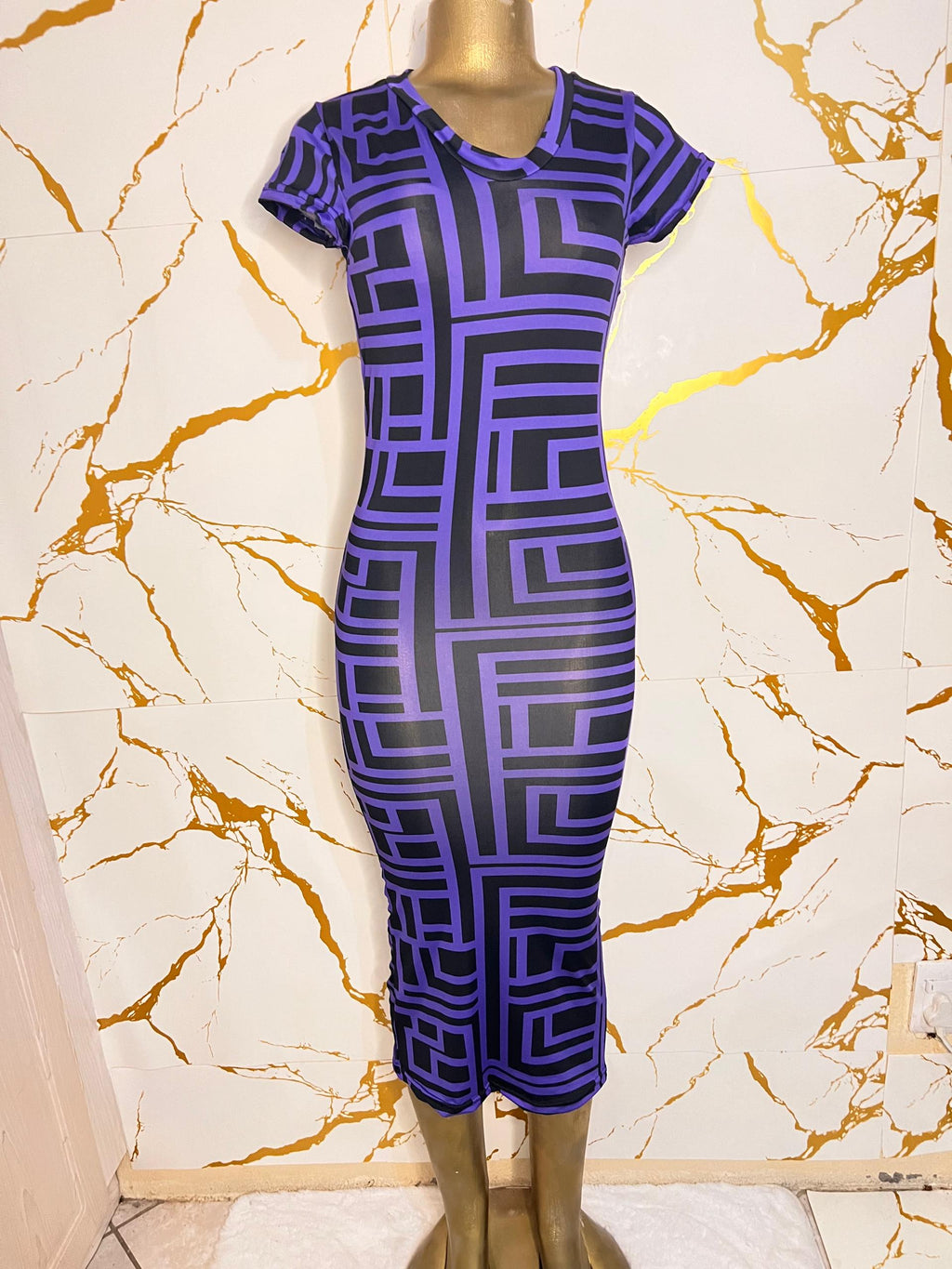 A short-sleeve, knee-length bodycon dress with a bold purple and black geometric maze pattern