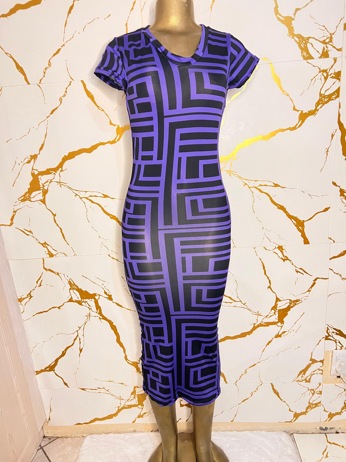 A short-sleeve, knee-length bodycon dress with a bold purple and black geometric maze pattern