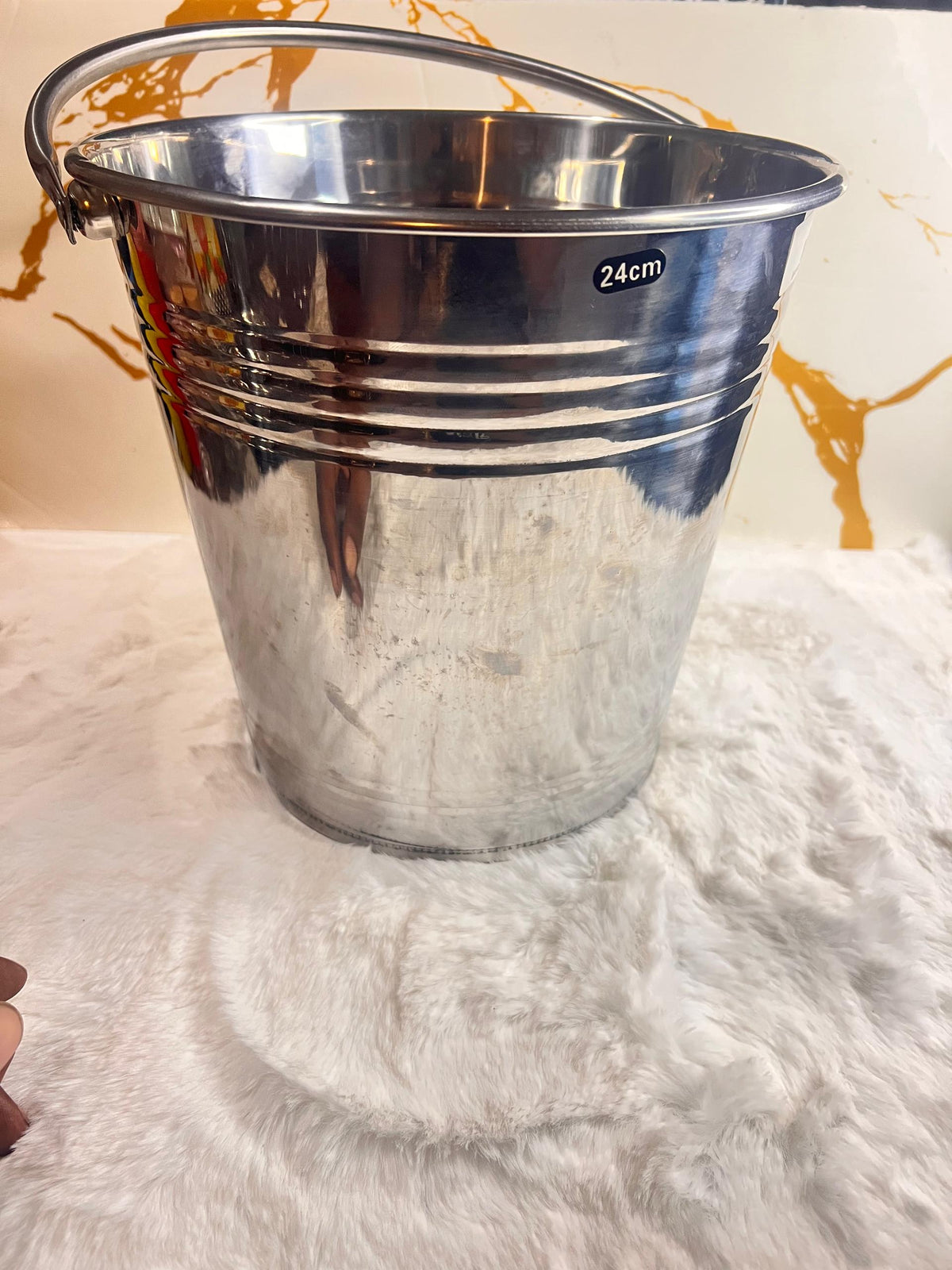 A shiny silver ice metal bucket with a curved handle