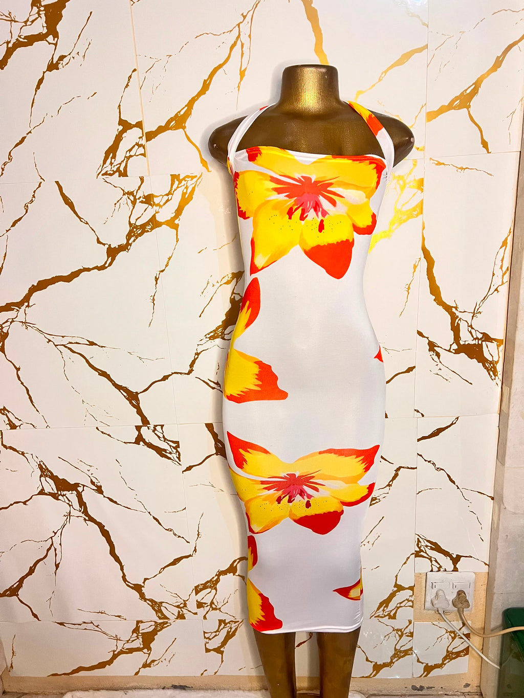white halter-neck bodycon dress with a bold yellow and orange flower print
