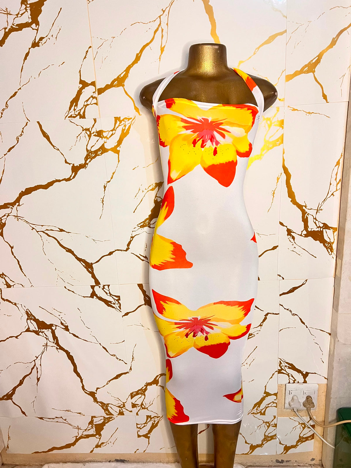 white halter-neck bodycon dress with a bold yellow and orange flower print