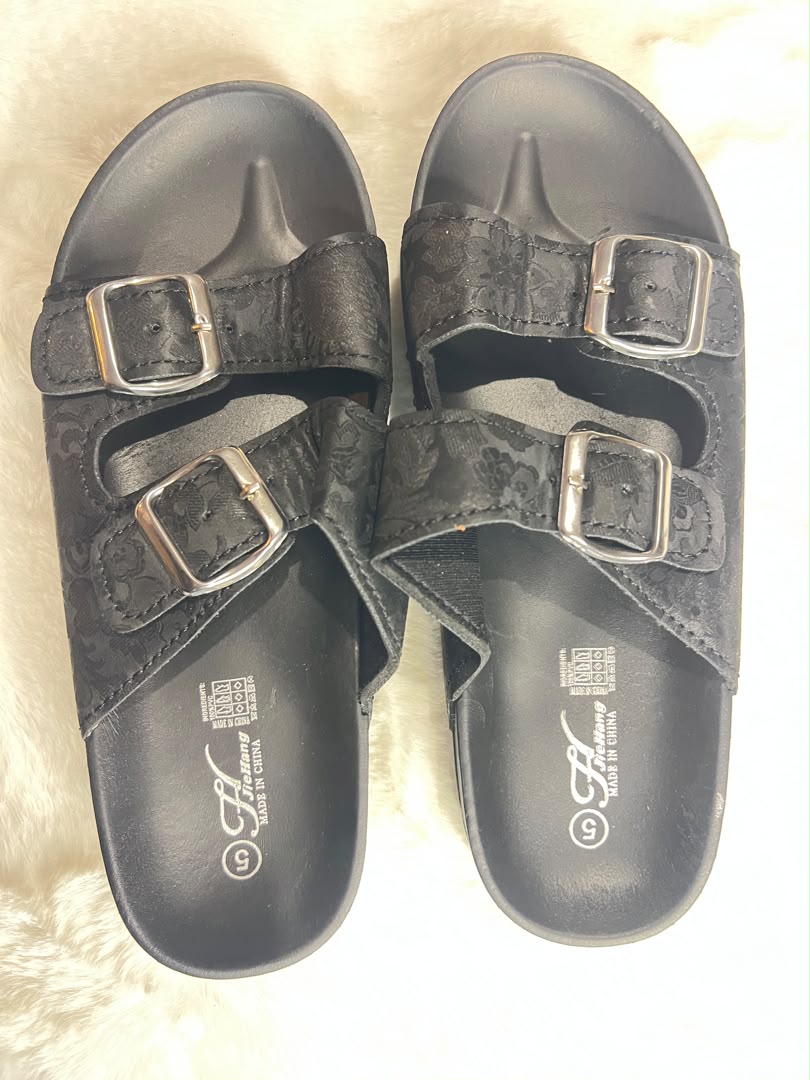 Black double-strap slide sandals with silver buckle closures