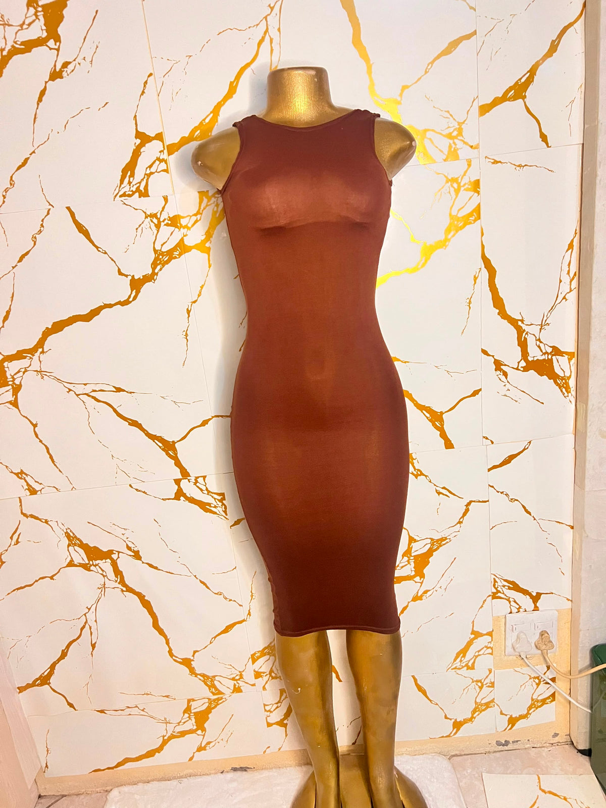 A sleeveless, bodycon midi dress in a warm rust brown color