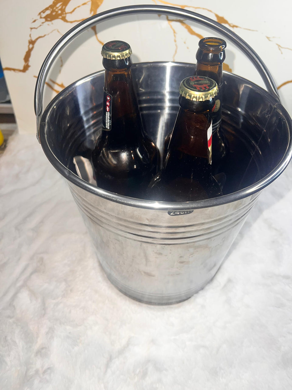 A shiny silver ice metal bucket with a curved handle