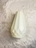 A faceted, geometric ceramic vase in a warm off-white