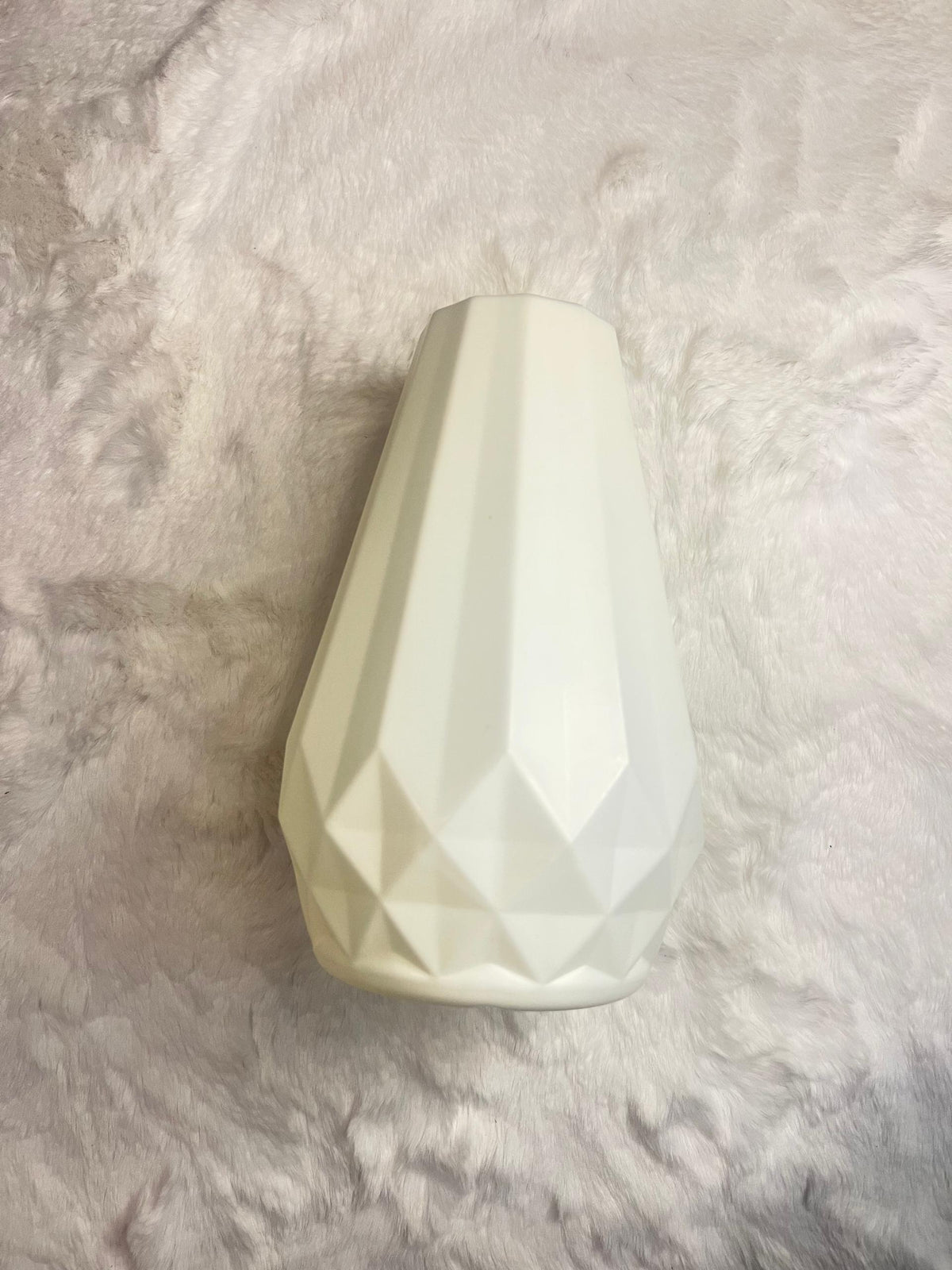 A faceted, geometric ceramic vase in a warm off-white
