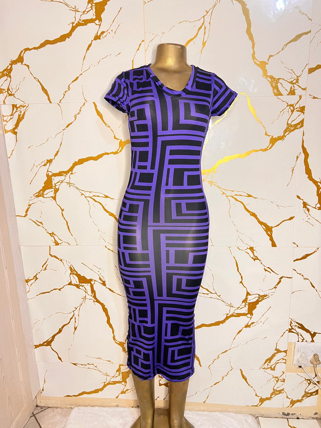 A short-sleeve, knee-length bodycon dress with a bold purple and black geometric maze pattern
