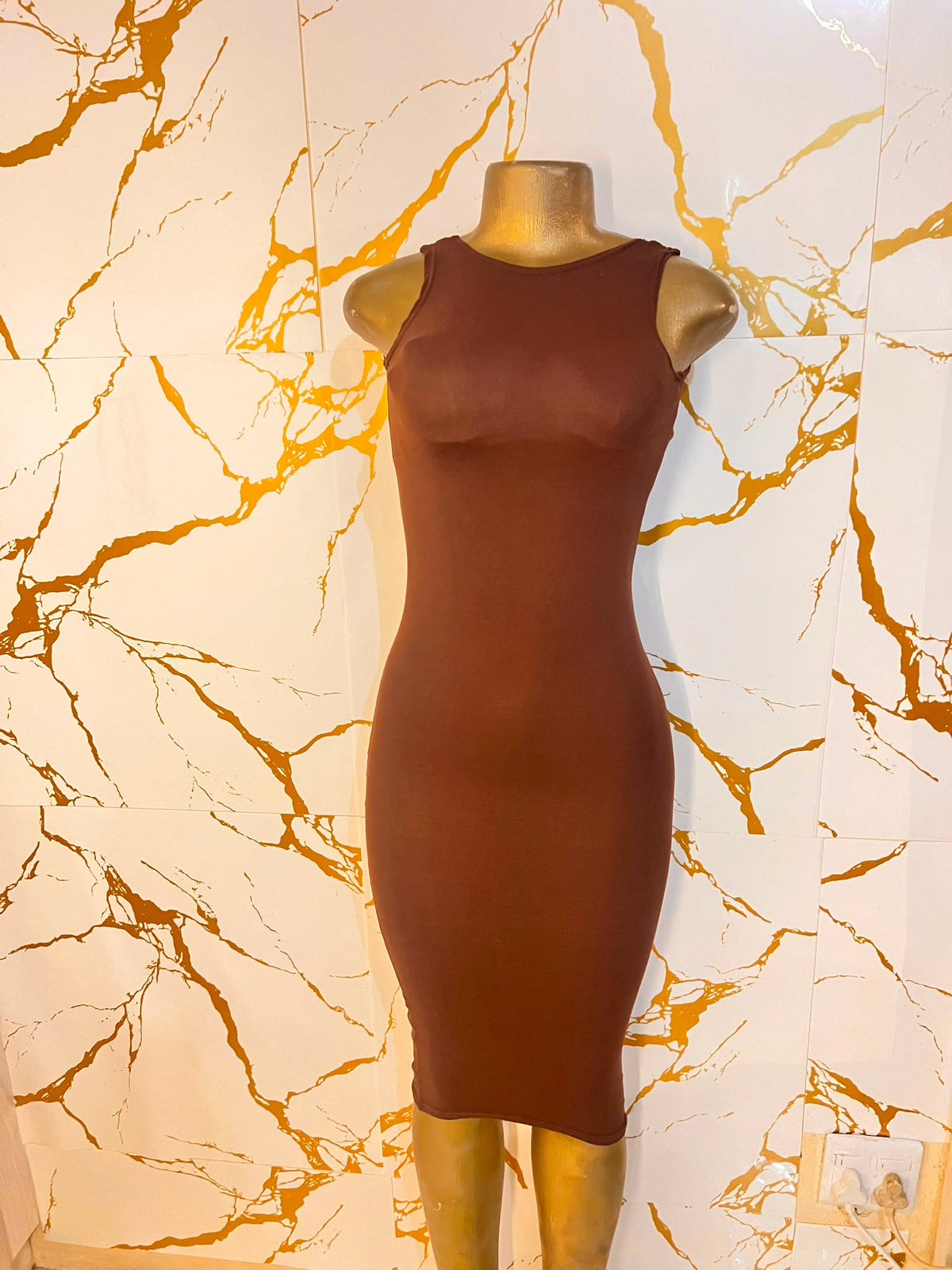 A sleeveless, bodycon midi dress in a warm rust brown color