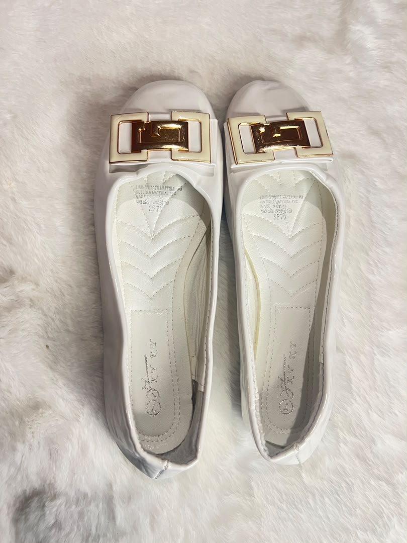 white leather ballet flats with a prominent gold-tone rectangular buckle